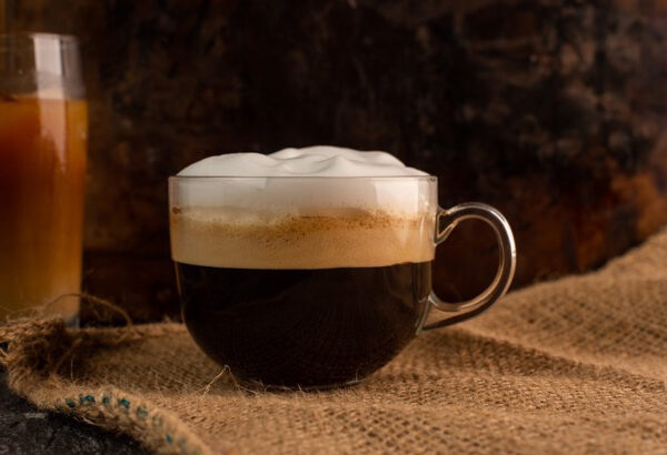 a glass of aromatic, fresh coffee with white, milk foam, on a rustic, warm background